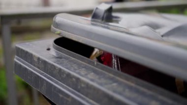 Çöp tenekesi kapağı aralığının yakın görüntüsü, içeriği ortaya çıkarıyor, doğal bir açık hava ortamında ayarlanıyor.