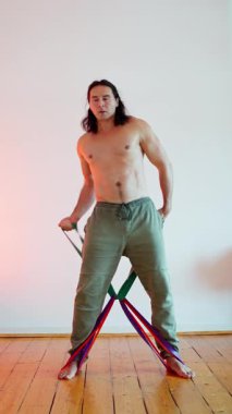 Bir birey direniş bantlarını kullanarak dinamik bir çömelip etkileyici bir denge ve güç gösterisi yapıyor.