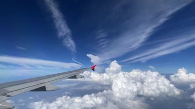 Nefes kesen hava manzarası güzel bir uçak kanadı gösteriyor kabarık bulutlar ve canlı mavi gökyüzü üzerinde süzülüyor. Fluffy Clouds 'un çarpıcı hava görüntüsü ve uçuş sırasında yakalanan bir uçak kanadı. 4k