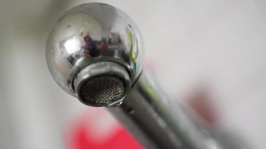 Krom musluğun yakın çekimi, akan su, sergilenen parlak tasarım ve modern banyo estetiği..