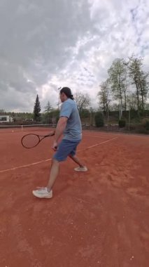 Dinamik bir tenisçi, killi bir sahada etkileyici atletizm ve becerilerini sergilerken yakalandı.