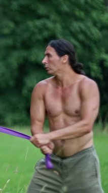 Kaslı bir adam enerjik bir doğa sporuna tutkulu bir şekilde bağlanır, canlı mor bir alet kullanır.