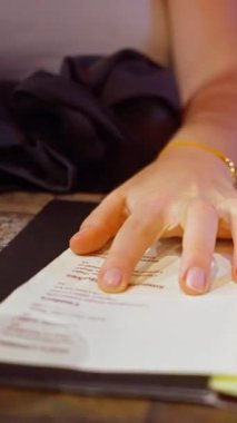 Bir kadın sıcak bir kafein ortamında menüye işaret eder, yemek seçeneklerini vurgular.