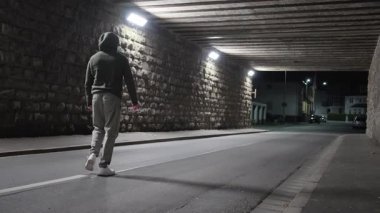 Huzurlu bir gecede, aydınlık bir tünelde yürüyen yalnız bir figür kentteki yalnızlığı somutlaştırıyor.