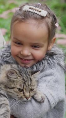 Neşeli bir kız, tüylü kedisini güzel doğal bir zemin üzerinde tutar, yürek ısıtan bir anı yakalar. Ağır çekim. Yüksek kalite 4k görüntü