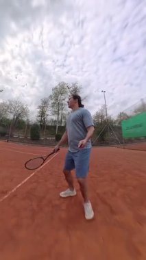 Yetenekli bir oyuncunun etkileyici yeteneklerini kil tenis kortunda sergilediği büyüleyici ve canlı bir sahne. Killi sahada tenis oynamanın dinamik ve heyecan verici eylemi. Ağır çekim. 4k