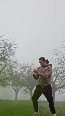 Bir boks uzmanı sisli bir alanda akarak dinamik hareketler ve eğitimdeki hassasiyeti gösterir. Ağır çekim. Sisli Açık Hava 'da Dinamik Eğitim. Yüksek kalite 4k görüntü