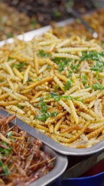 Canlı, hareketli bir pazarda bir dizi kızarmış böcek ve çeşitli lezzetli sokak atıştırmalıkları keşfedin.