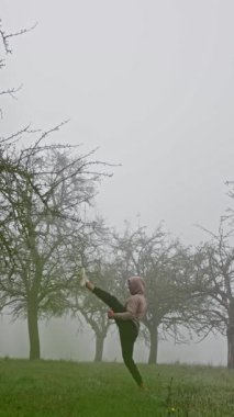 Bir dövüş sanatları uzmanı sisli bir alanda akarak dinamik hareketleri ve eğitimdeki hassasiyeti gösterir. Ağır çekim. Sisli Açık Hava 'da Dinamik Eğitim. Yüksek kalite 4k görüntü