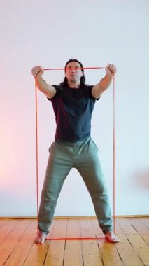 Bir adam çarpıcı bir sanatsal ortamda elastik bant kullanarak olağanüstü bir güç ve esneklik sergiliyor. EyeCatching 'in elastik bant kullanarak geliştirdiği Dinamik Fitness Uygulamasında aktif olarak yer alıyor.