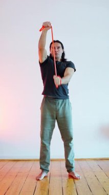 Bir adam esnekliğini artırmak için direnç aracı kullanırken dinamik bir esneme hareketi sergiliyor.