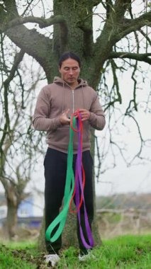 Parkta egzersiz yapan bir adam, direniş bantlarını kullanarak etkili bir şekilde güç eğitimine katılıyor. Daha Sağlıklı Olmak İçin Direnç Bantlarıyla Açık Hava Fitness Gücü Eğitim Seanslarına katılıyoruz. Yüksek kalite 4k