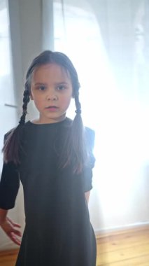 Çarşamba konsepti giyen genç bir kız. Çocuk Dansı. Çarşamba kostüm tarzı siyah bir elbise içinde dans ediyorlar. Ağır çekim. Yüksek kalite 4k görüntü