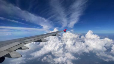 Nefes kesen hava manzarası güzel bir uçak kanadı gösteriyor kabarık bulutlar ve canlı mavi gökyüzü üzerinde süzülüyor. Fluffy Clouds 'un çarpıcı hava görüntüsü ve uçuş sırasında yakalanan bir uçak kanadı. 4k