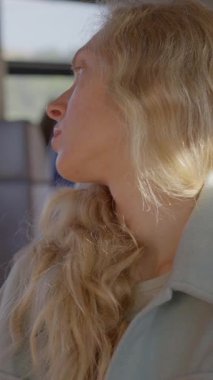 Uzun, dalgalı saçları olan genç bir kadın tren yolculuğunun tadını çıkarırken pencerenin kenarında huzur içinde dinleniyor. Ağır çekim. Yüksek kalite 4k görüntü