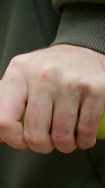 Yakından, parktaki jimnastik barlarında egzersiz yapan bir adam. Şınav çekiyorum. Ağır çekim. Yeşil kapüşonlu genç bir adam canlı bir oyun alanında parlak ve canlı sarı bir çubuğu sıkıca kavrıyor.