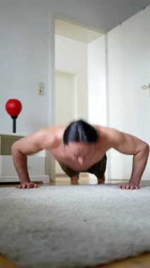 Halılı zeminde şınav çeken bir adam spor ve güç eğitimine kendini adamış..