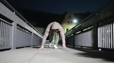 Adam gece vakti loş bir köprüde şınav çekiyor, zindelik ve kararlılık gösteriyor. Gece vakti loş bir köprüde şınav çekmek, zindelik ve kararlılık gösterisi. 4k