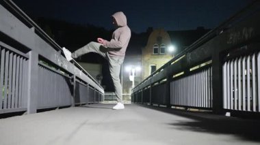 Bu dinamik ortamda kentsel zindelik gösteren, gece boyunca bir köprüde kibarca gerinen bir insan.