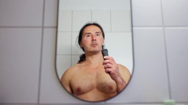 Bir adam burnundaki kılları elektrikli budayıcı ile alıyor. Burun kılları alınıyor, yakın plan. Yüksek kalite 4k görüntü