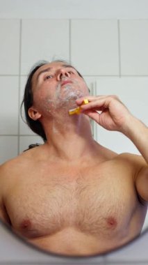 Bir adam banyoda tıraş oluyor, kişisel bakım ve kişisel bakım rutinlerinin önemini gösteriyor. Yüksek kalite 4k görüntü