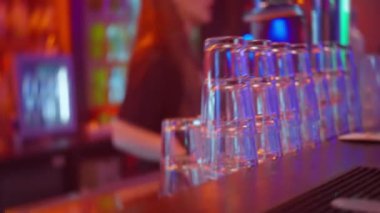 Canlı bir bar sahnesi canlı, renkli bir arkaplana karşı dizilmiş muhteşem bir istiflenmiş gözlük gösterisi sunar.