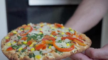 Fırından çeşitli renkli malzemelerle dolu taze pişmiş sebze pizzası çıktı.