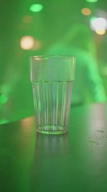 Canlı ve aydınlık bir bar sahnesi. Renkli gözlükler. Elektrikli kulüp ışıklandırmasına karşı ayarlanmış. Ağır çekim. Yüksek kalite 4k görüntü