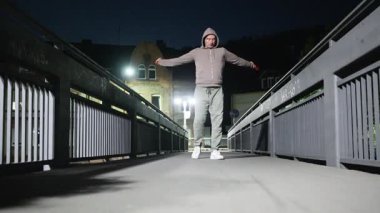 Bir adam geceleri köprüde direnç bandı egzersizleri yapıyor. Güçlerini ve zindeliklerini ön plana çıkarıyor. Yüksek kalite 4k görüntü