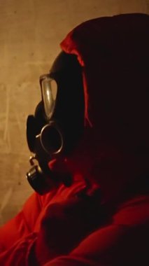 Kırmızı bir kapüşonlu ile eşleştirilmiş gaz maskesi takan gölgeli bir figür inanılmaz ürkütücü bir atmosfer yaratıyor.