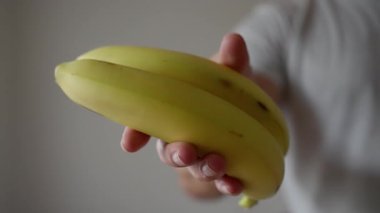 Güçlü vejetaryen, vegan adam, kaslarını gösteriyor. Sıcak ve davetkar bir ortamda, bir insan canlı olgun muzlar sunar, ilgi ve haz çeker. Yüksek kalite 4k görüntü