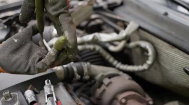 Yetenekli bir tamirci bir araba üzerinde çalışırken çeşitli araçlar kullanır ve motor parçalarını özenle onarır.