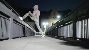 Kendini işine adamış ve tutkulu bir atlet, ıssız bir gece köprüsünde etkileyici bir tekme hareketi sergiliyor.