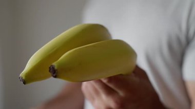 Vegan Adam, kaslarını gösteriyor. Sıcak ve davetkar bir ortamda, bir insan canlı olgun muzlar sunar, ilgi ve haz çeker. Güçlü vejetaryen, yüksek kalite 4K görüntü