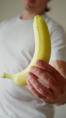 Taze, olgun bir muz sergileyen bir birey, sağlık ve keyif dolu canlı bir anı yakalıyor.