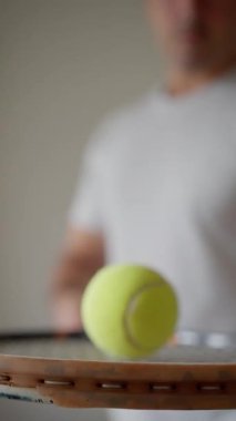 Erkek kol raketi tutuyor ve küçük sarı topa vuruyor. Tenis oyuncusu sahada antrenman yapıyor. Ağır çekim. Dikey görünüm. Yüksek kalite 4K görüntü. Yüksek kalite 4k görüntü