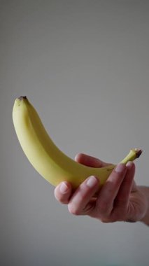 Havada Dönen Muz, Beyaz Arkaplanda Bir Erkek El Tarafından Fırlatılıp Yakalandı, İzole Yavaş Hareket. Dikey video. Yüksek kalite 4k görüntü