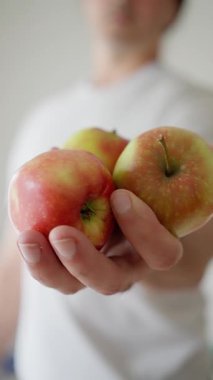 Mutlulukla taze elmalar tutan bir insan, enerji ve sağlıkla dolu sağlıklı ve hayat dolu bir yaşam tarzını yansıtıyor.