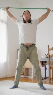 Bir kişi evdeki direnç bantlarıyla çalışıyor, hem fitness seviyesini hem de esnekliği arttırmayı hedefliyor. Yüksek kalite 4k görüntü