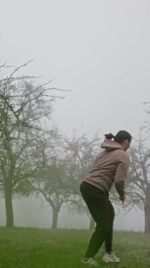 Yetenekli bir dövüş sanatçısı, güçlü ve etkileyici tekniklerini güzel sisli bir ortamda sergiliyor. Ağır çekim. Dikey video. Yüksek kalite 4k görüntü