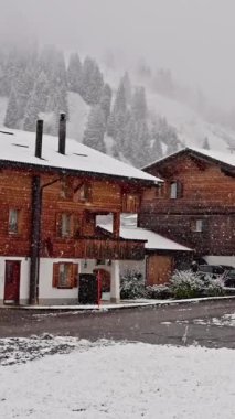 Karda güzelce ıslanmış, hoş, rahat bir ahşap köy manzarası huzurlu bir kış manzarası yaratıyor. İsviçre montajı. Yüksek kalite 4k görüntü