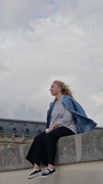 Louvre Müzesi 'ne yansıyan genç bir kadın, tarihsel mimariye karşı modern moda sergiliyor..