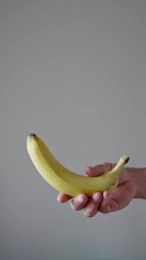 Havada Dönen Muz, Beyaz Arkaplanda Bir Erkek El Tarafından Fırlatılıp Yakalandı, İzole Yavaş Hareket. Dikey video. Yüksek kalite 4k