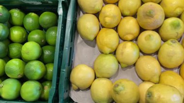 Canlı ve göz kamaştırıcı taze, sulu limon ve limon dolu yeşil sandıklar içinde kalabalık bir yerel pazarda.