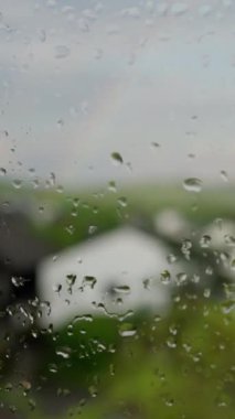 Güzel bir yakın çekim yağmurlu bir pencereyi yakalar, Bulanık yeşilliği ve dışarıdaki rahat evi vurgular