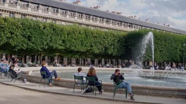 Fransa. Paris mi? 12 04 2024. Neşeli bir grup ziyaretçi, güzel bir çeşmesi ve yemyeşil yemyeşil bir bahçesinde güneşli bir günün tadını çıkarıyor. Yavaş çekim