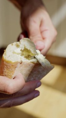 Taze ekmek ve tereyağlı rulo ekmeği ve bıçağı ustalıkla tutan bir elin yakından çekimi. Lezzetli bir aperatifin tadını çıkarmaya hazır. Lezzetli bir aperatifin zevkini çıkarıyorum. Sıcak bir mutfak ortamında keskin bir bıçak kullanıyorum.