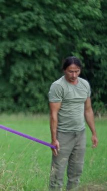 Yeşillik bir alanda direnç bantlarını kullanarak çeşitli güçlü eğitim tekniklerini ustalıkla sergileyen bir kişi. Yüksek kalite 4k görüntü