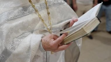 Tören kıyafeti giymiş bir rahip önemli bir dini tören sırasında kutsal bir kitap tutuyor.