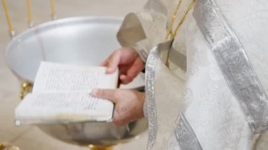 Kutsal giysiler giymiş bir rahip, kutsal bir vaftiz töreni düzenler. Su havzası ve mumlarla. Yüksek kalite 4k görüntü